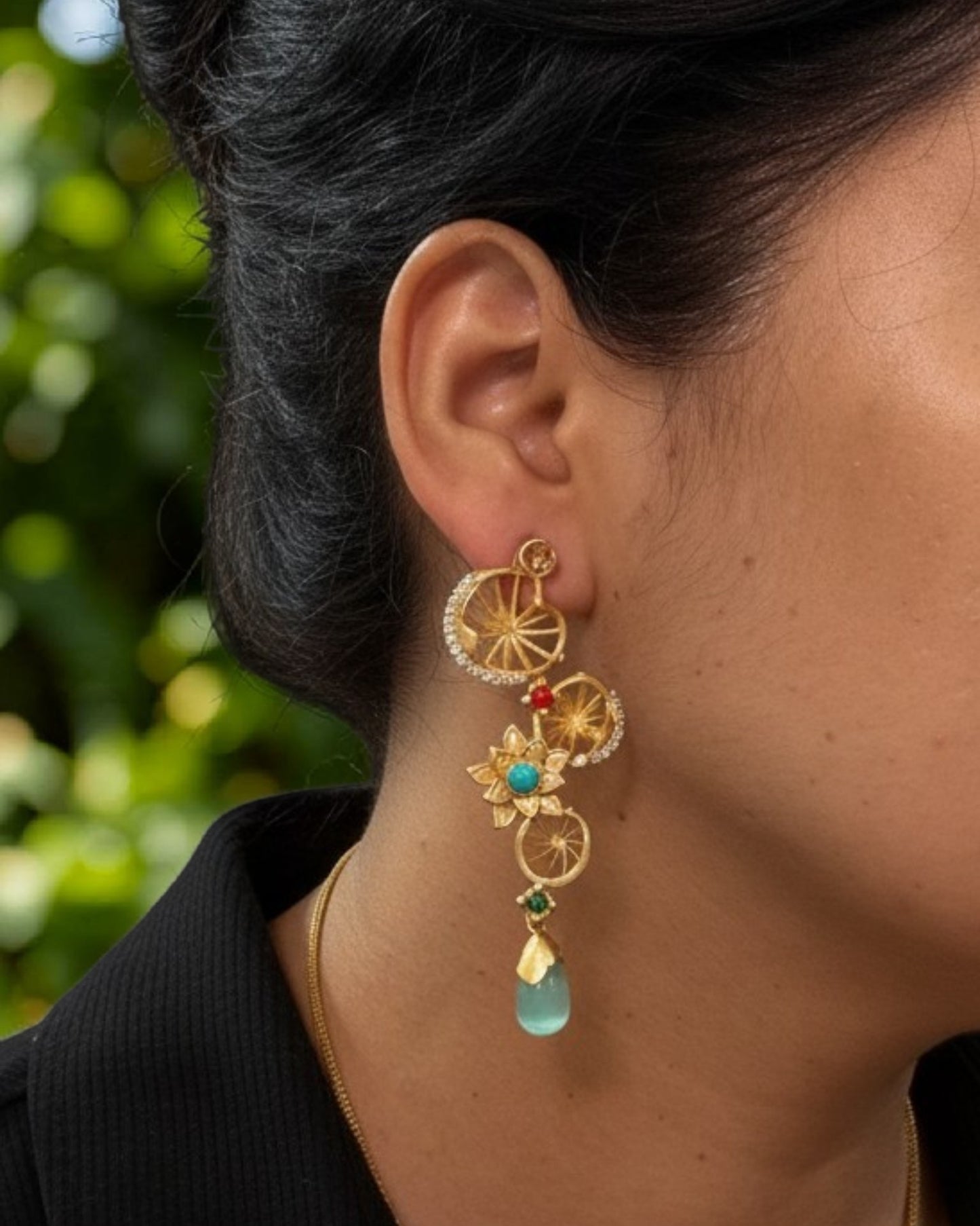 Statement brass dangler earrings featuring AD stones and decorative floral accents.