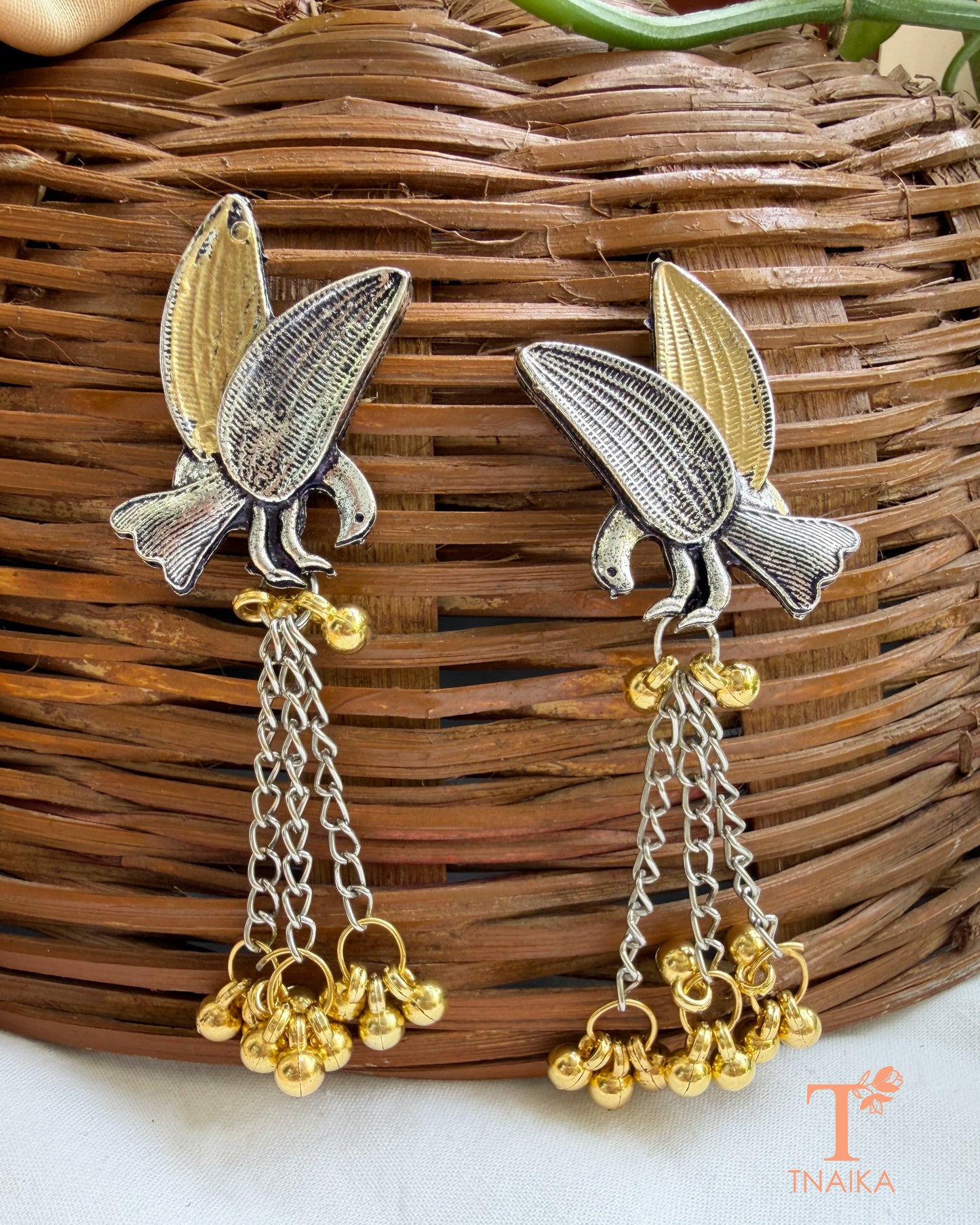 Artistic bird motif statement earrings with chain and bell detailing.