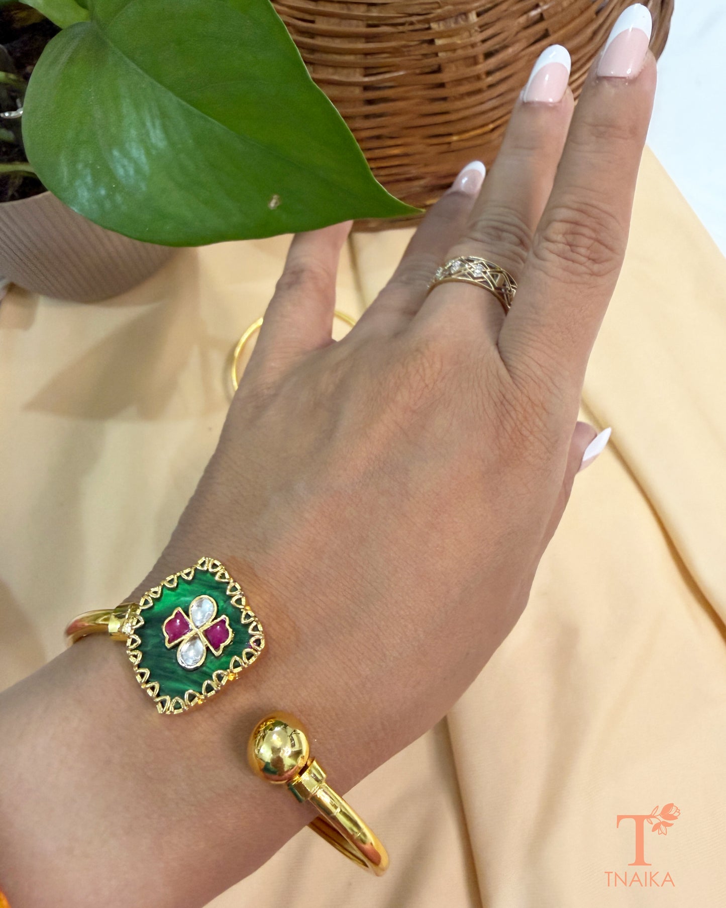 Traditional adjustable brass bracelet with green enamel, kundan stones, and polished gold finish.