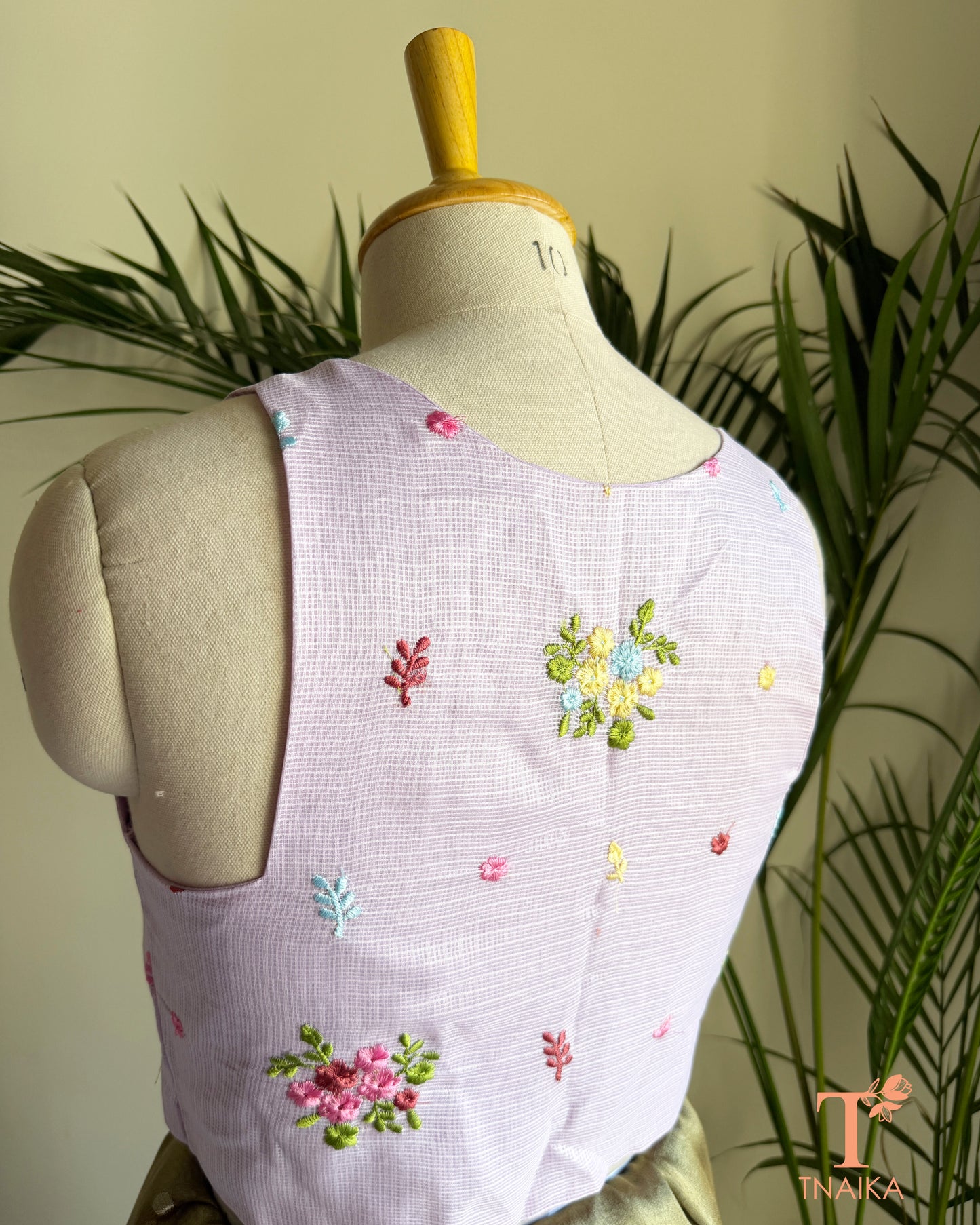 Back view of premium embroidered Kota silk blouse featuring delicate floral motifs, soft pastel embroidery, and a structured tailored finish.