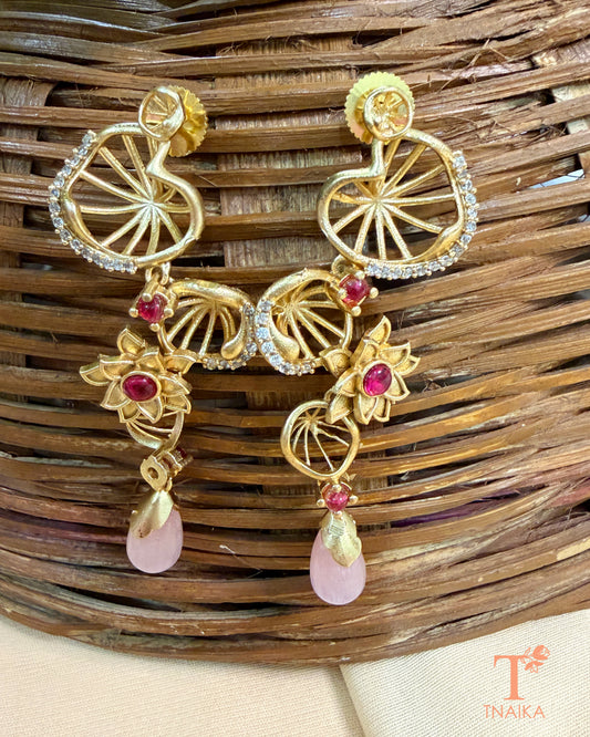 Statement brass dangler earrings featuring AD stones and decorative floral accents.