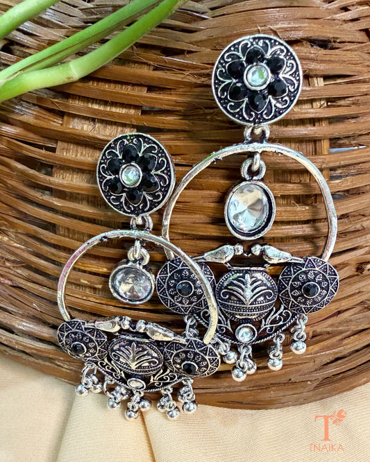 Traditional oxidised statement earrings featuring green stones and dangling accents.