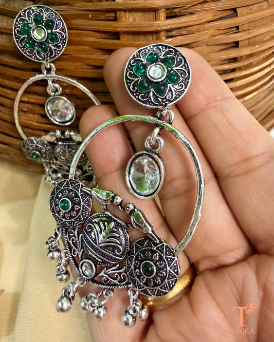 Traditional oxidised statement earrings featuring green stones and dangling accents.