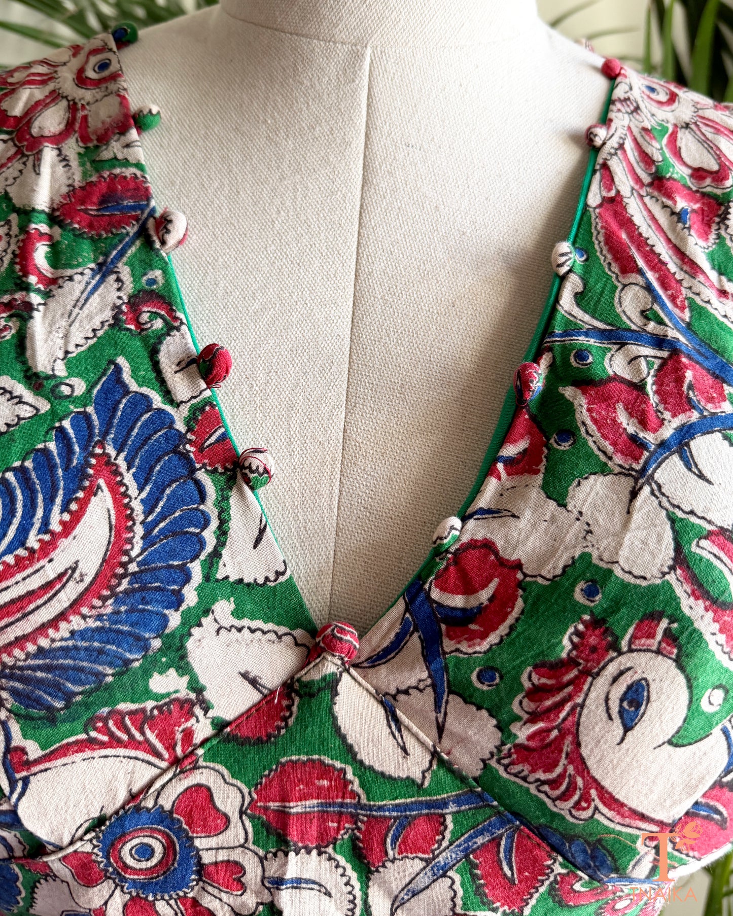 Detailed view of the V-neckline with handcrafted fabric potli embellishments on a multicolor Kalamkari cotton blouse by Tnaika™.