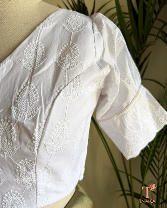 Side profile of white cotton blouse showcasing embroidered puff sleeve detailing.