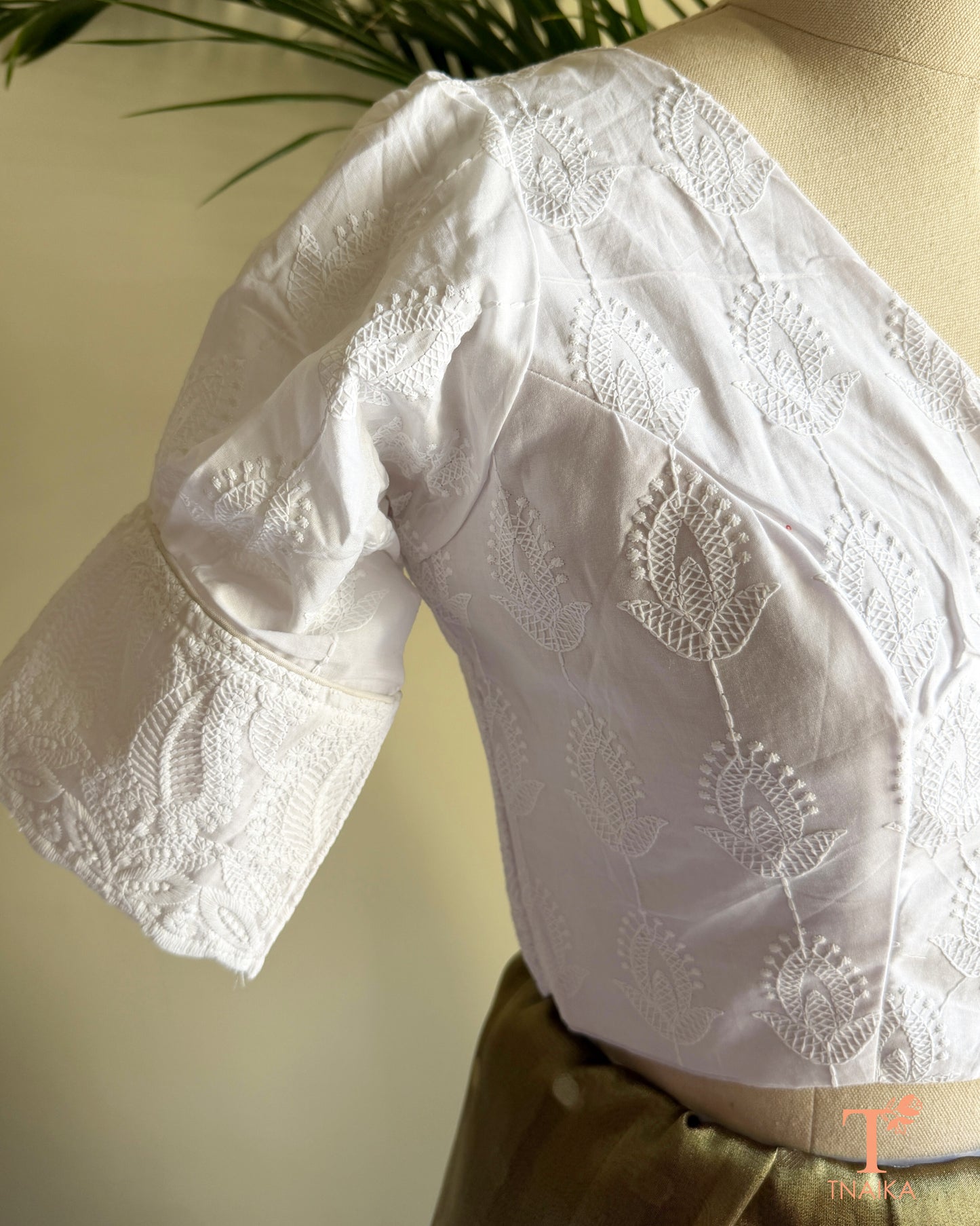 Side profile of white cotton blouse showcasing embroidered puff sleeve detailing.