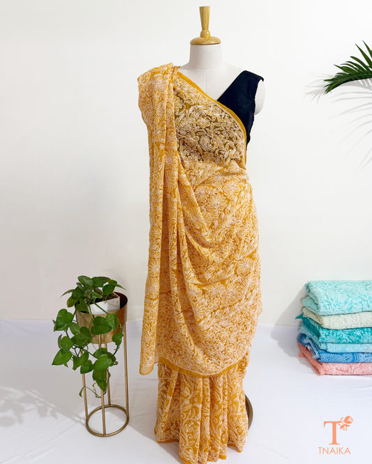 Mustard Yellow Chikankari georgette saree with intricate white floral embroidery.