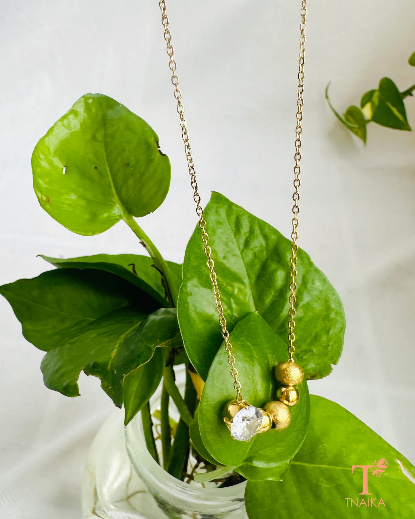 Gold tone anti-tarnish necklace with a sparkling crystal centerpiece and delicate bead detailing.