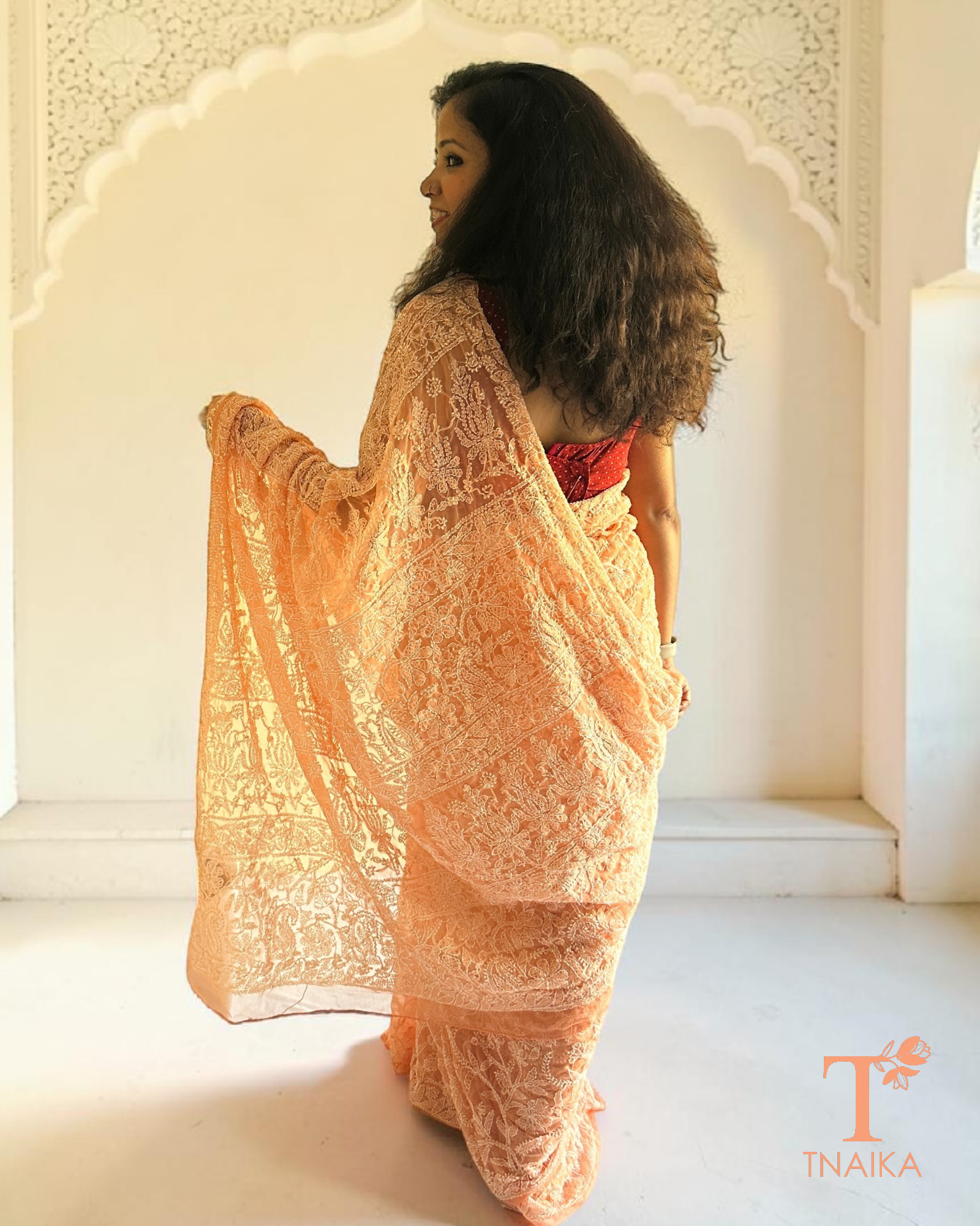 Peach georgette saree featuring traditional chikankari embroidery throughout