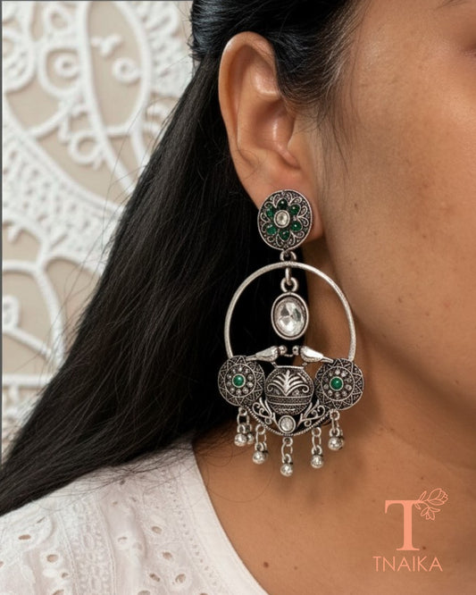 Oxidised silver tone earrings with green stone work and intricate ethnic detailing.