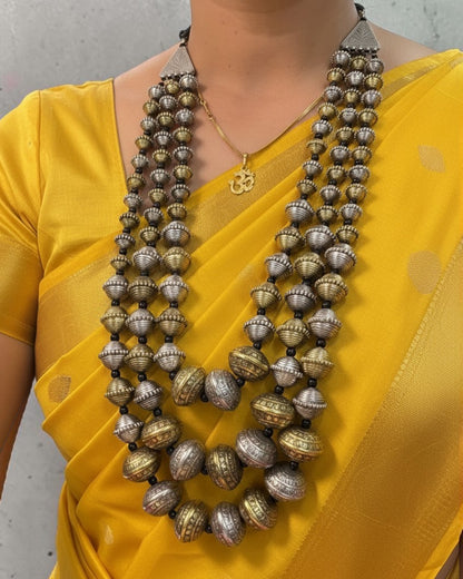 Model wearing the Kanak Layered Bead Mala with dual-tone oxidised engraved beads, styled with a yellow saree for a traditional ethnic look.