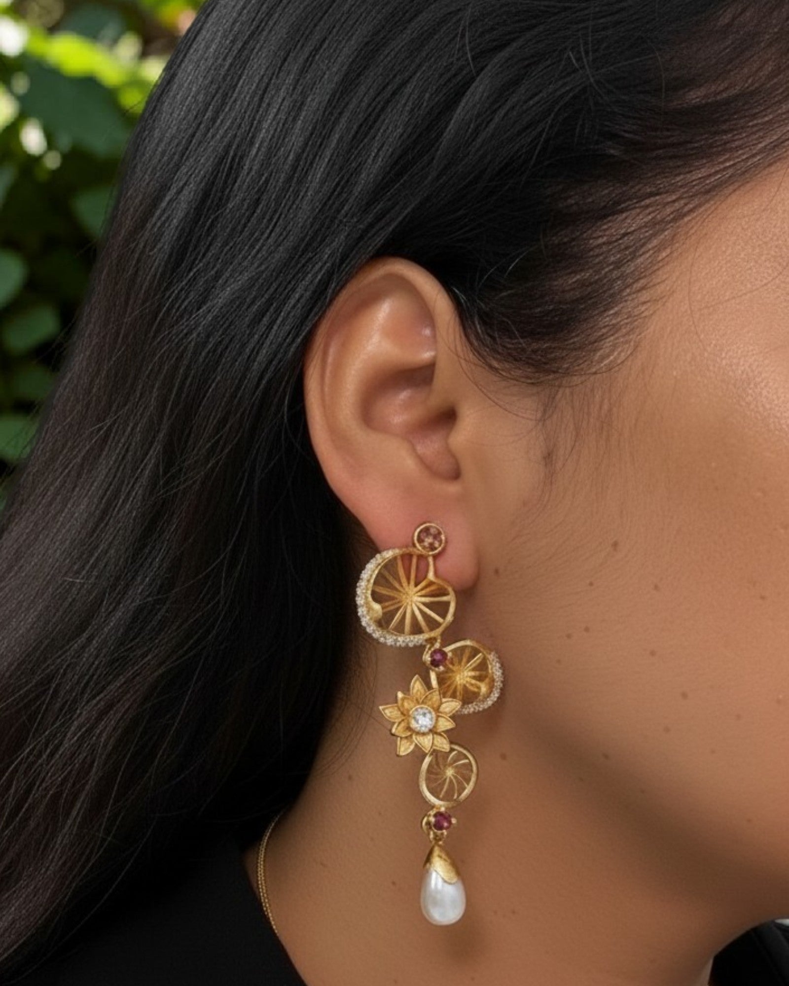 Statement brass dangler earrings featuring AD stones and decorative floral accents.