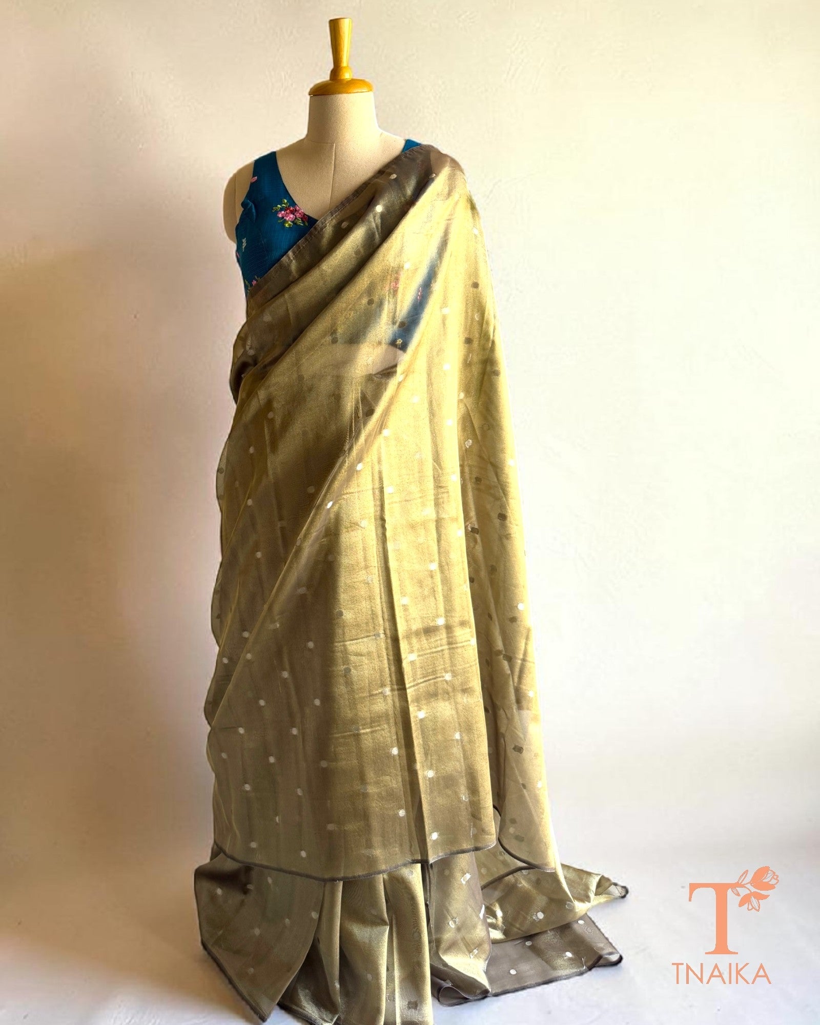 Elegant olive tissue silk saree styled with a contrasting blue embroidered blouse.