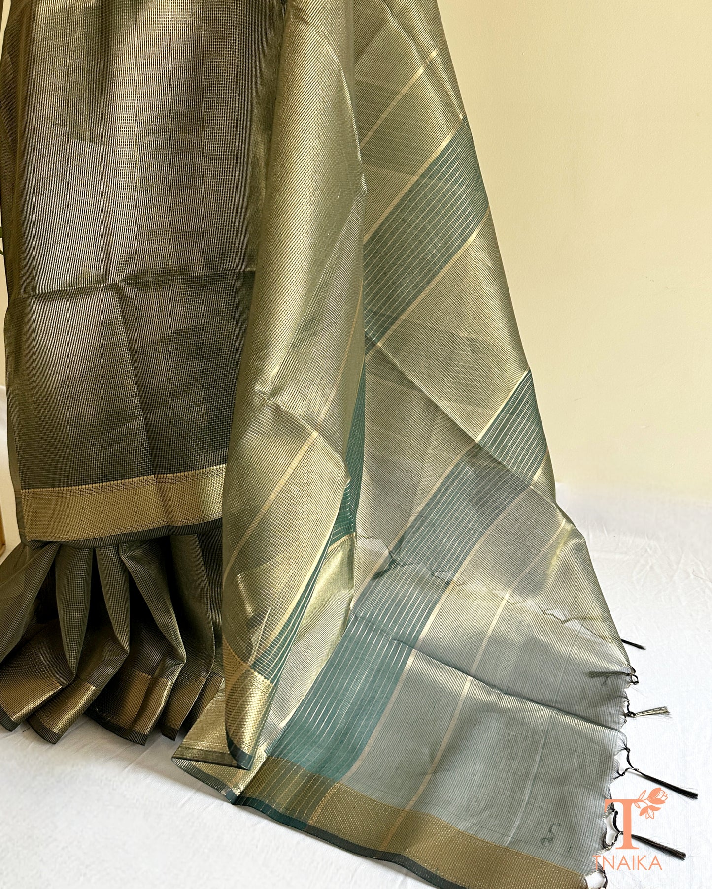 Elegant muted green tissue silk checks saree with luminous sheen, woven zari borders, and tassel pallu accents
