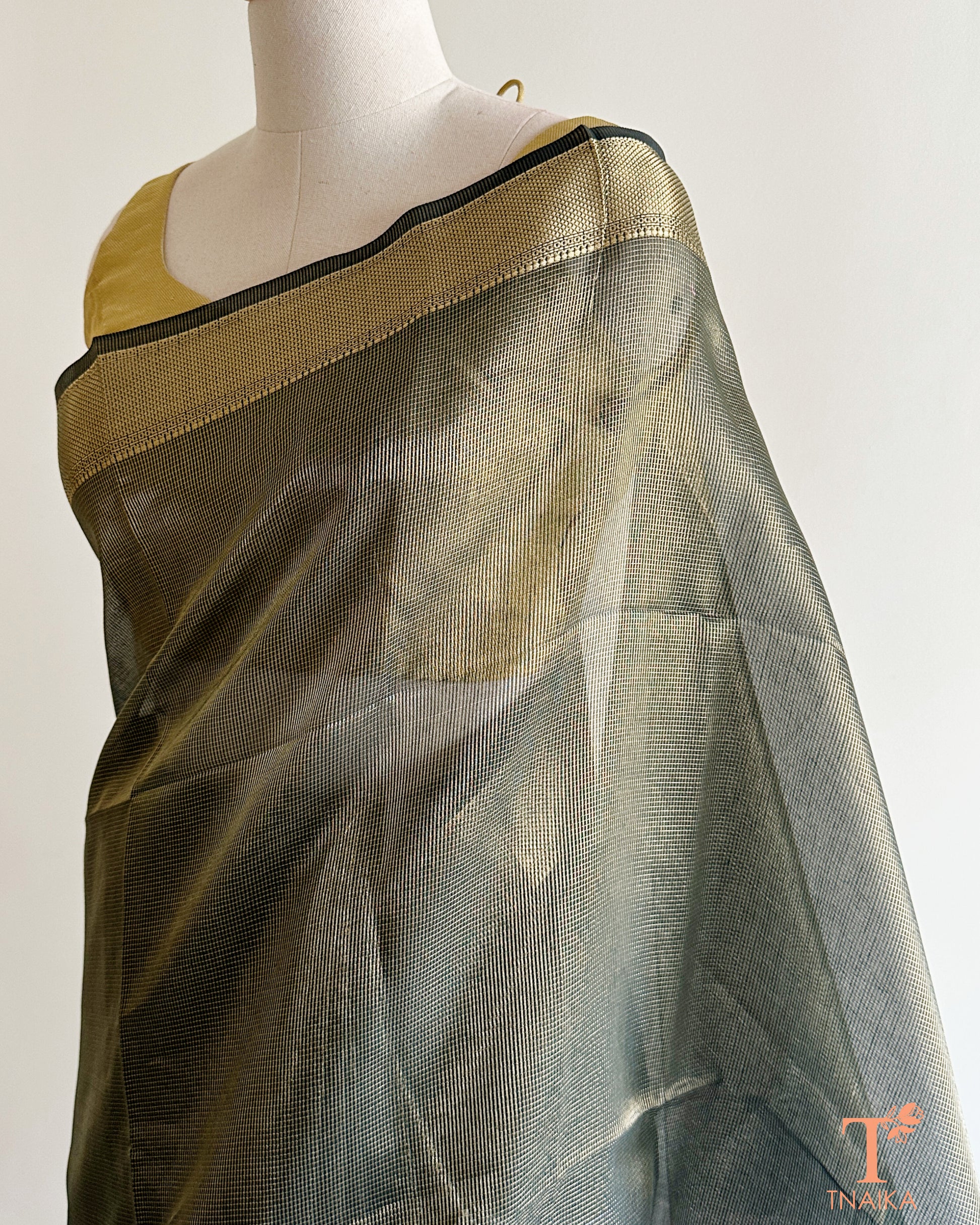 Close-up of muted olive green tissue silk saree featuring fine micro checks, antique gold zari weave, and striped pallu design