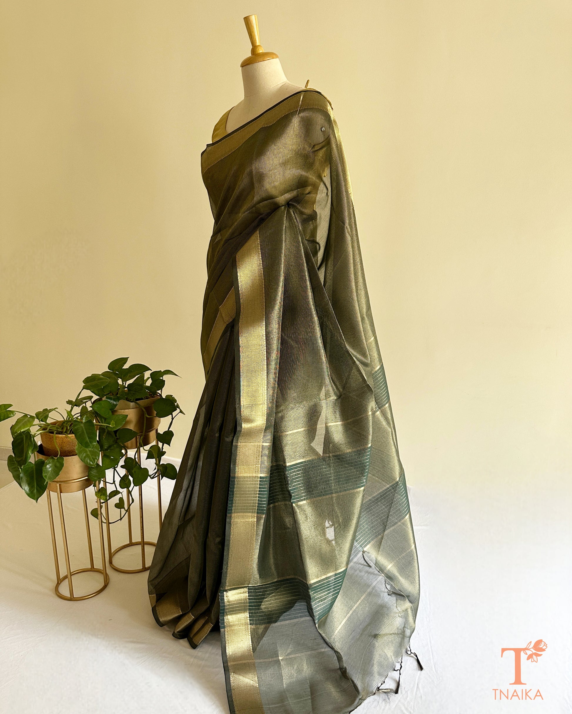Festive muted dark olive tissue silk saree with airy translucent drape, broad zari borders, and elegant tassel finish