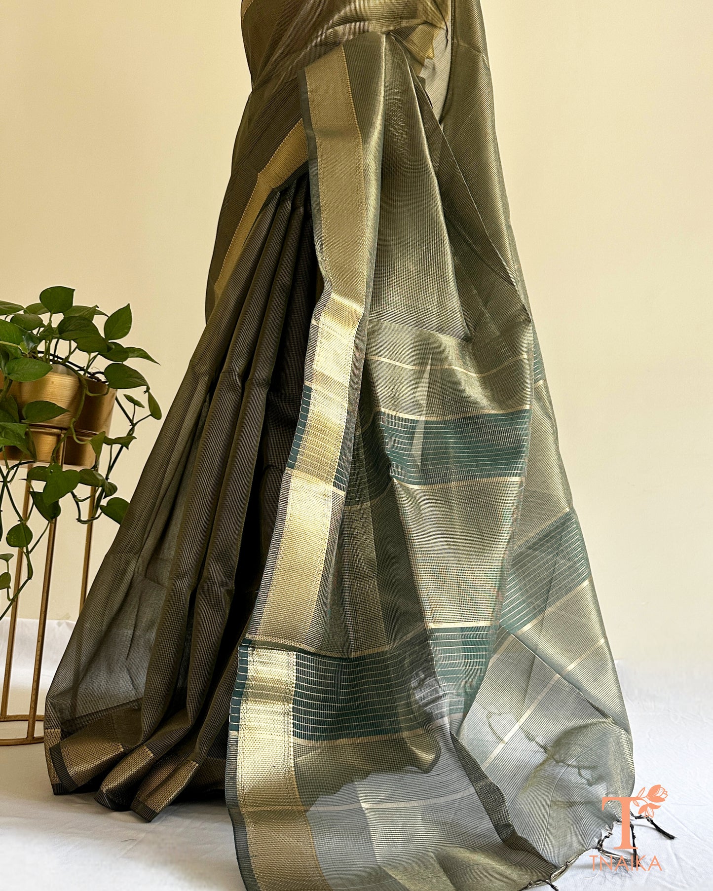 Muted dark green tissue silk saree with golden zari border and striped pallu detailing in lightweight festive drape