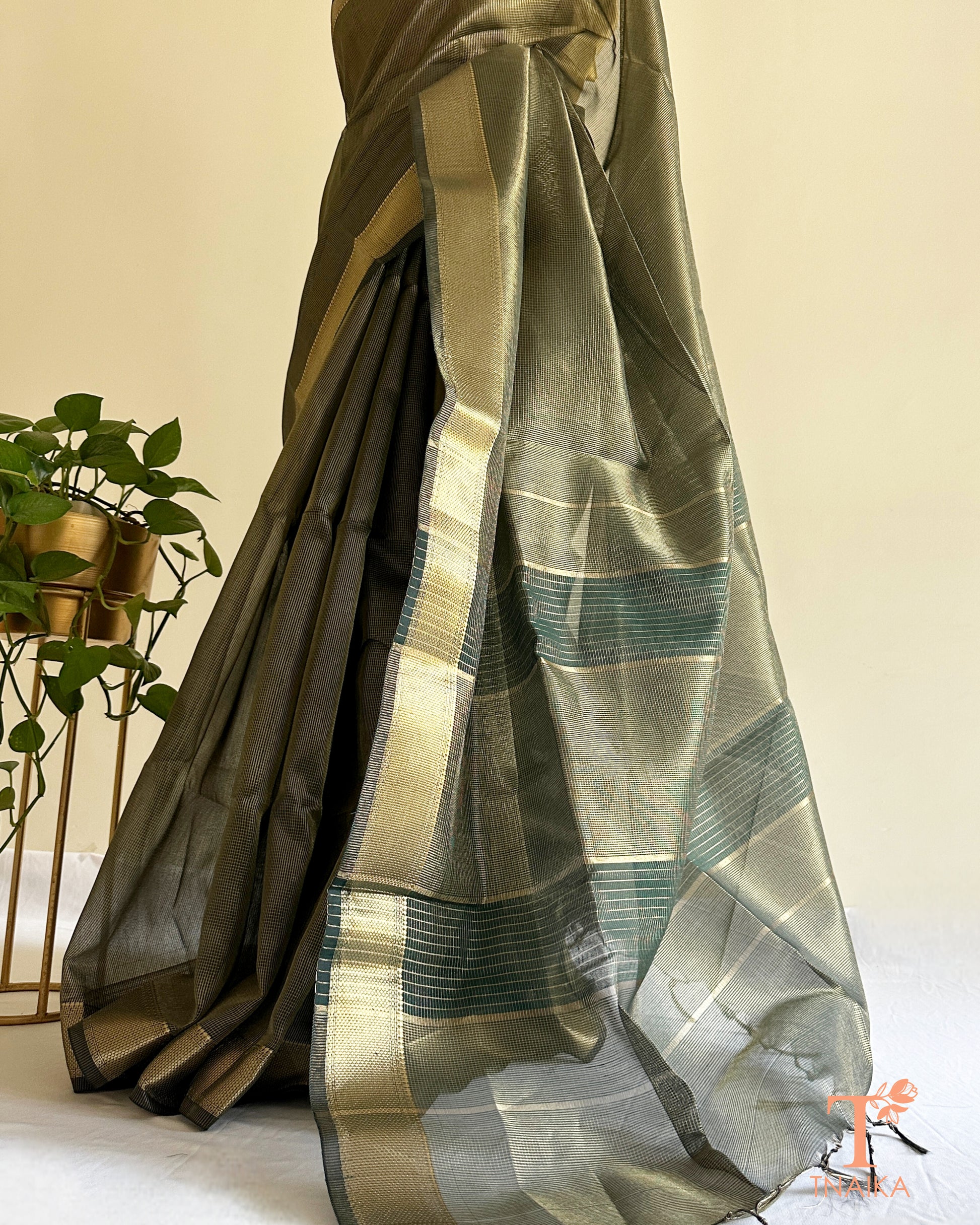 Muted dark green tissue silk saree with golden zari border and striped pallu detailing in lightweight festive drape