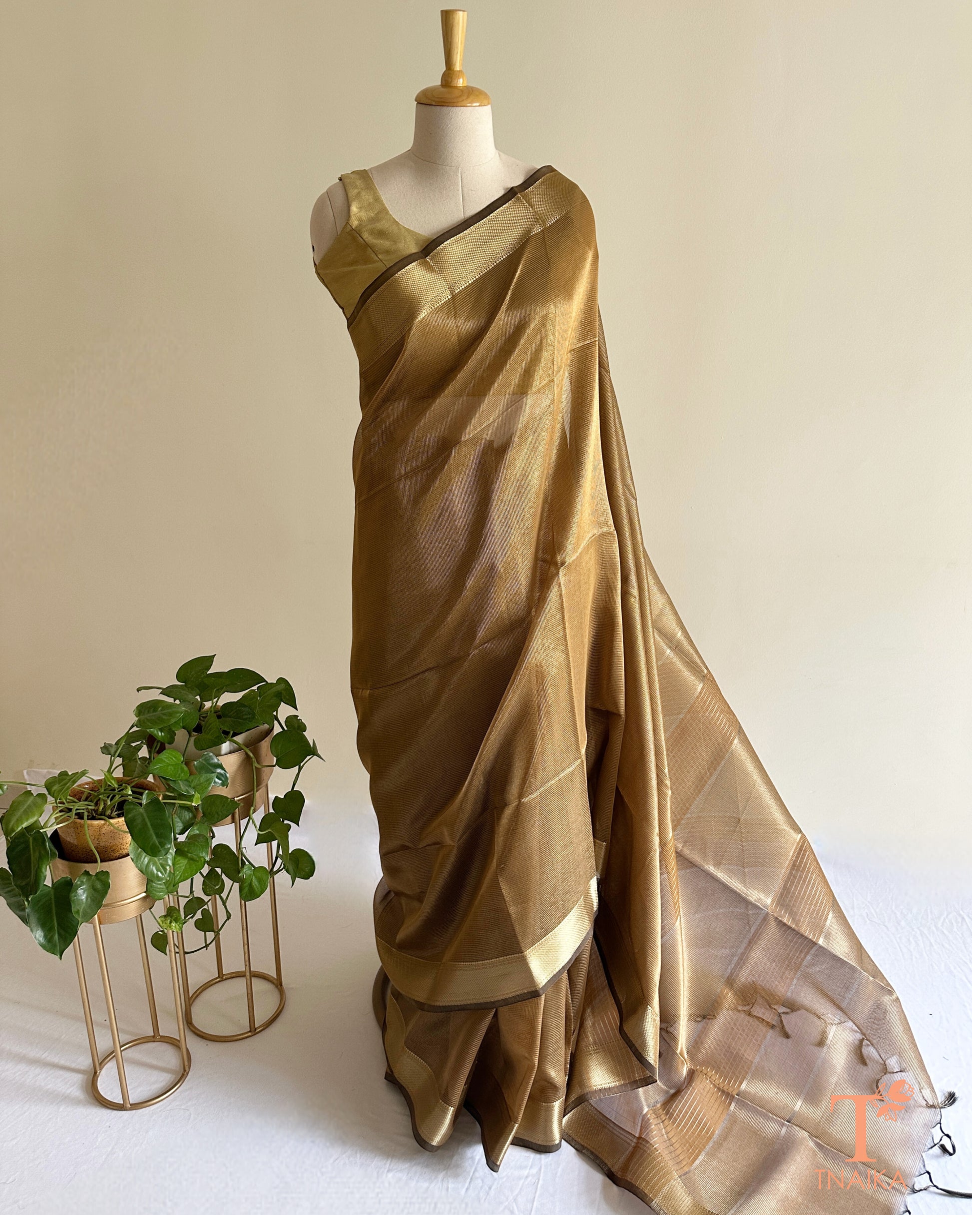 Muted bronze gold tissue silk saree with soft shimmer, woven zari borders, and elegant striped pallu detailing