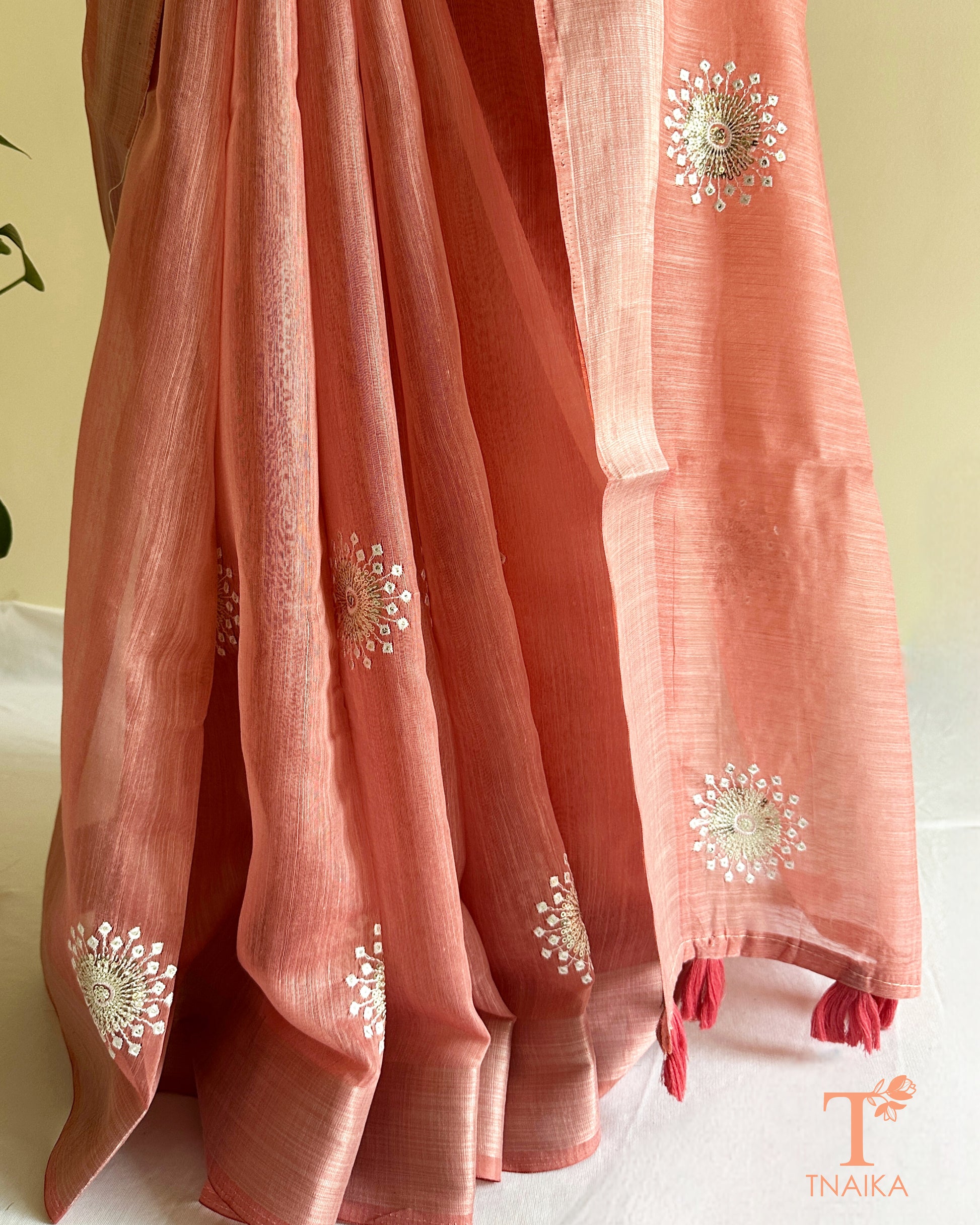 Lightweight pastel pink cotton saree featuring subtle embroidery and tassel pallu detailing