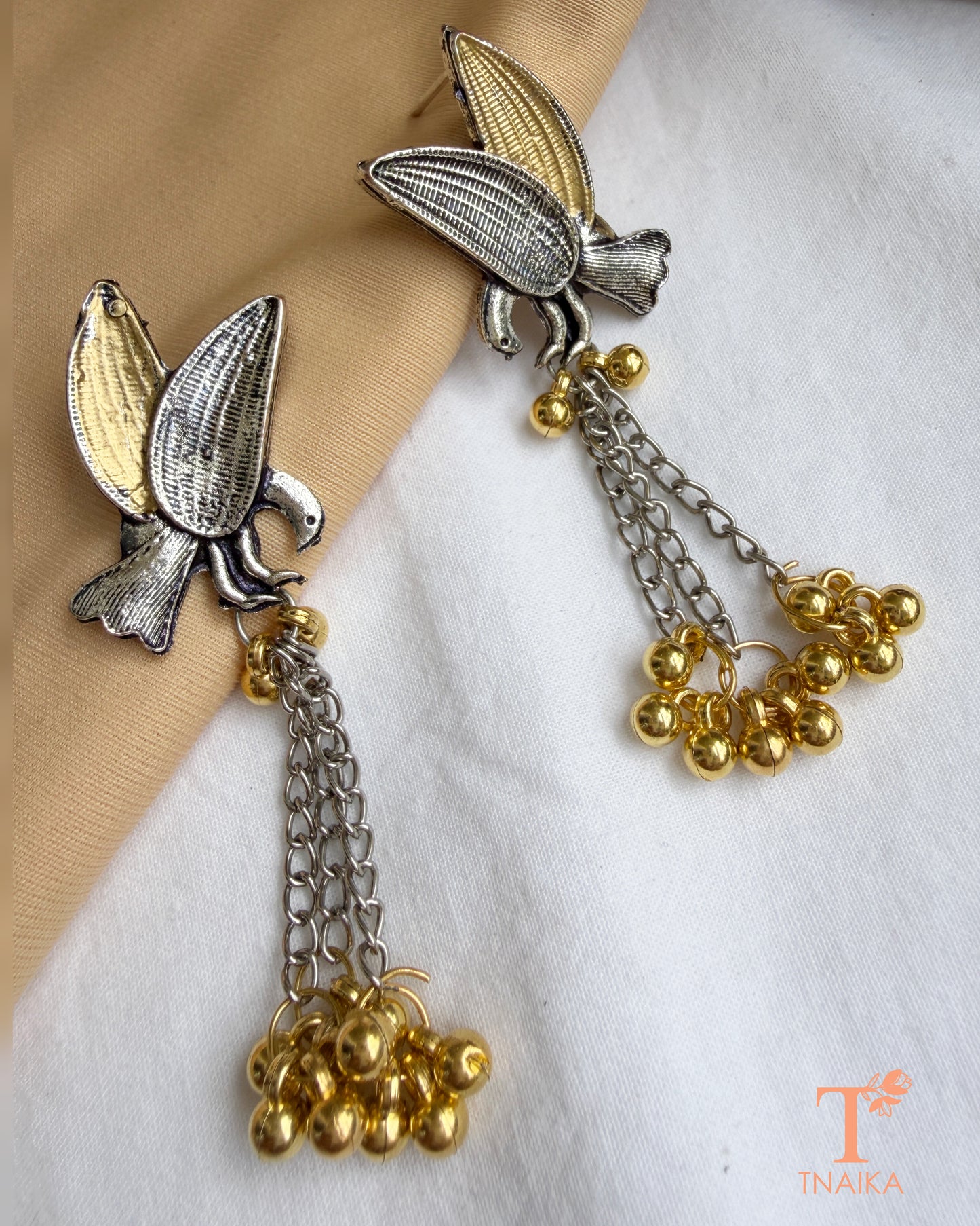 Nature inspired silver replica dangler earrings with textured bird design.