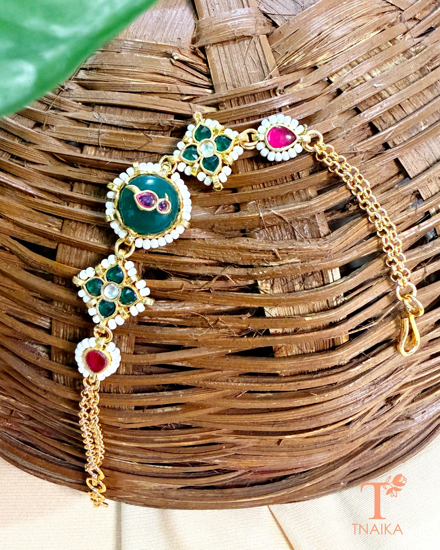 Ethnic brass bracelet with green enamel centerpiece and ruby-toned kundan accents.