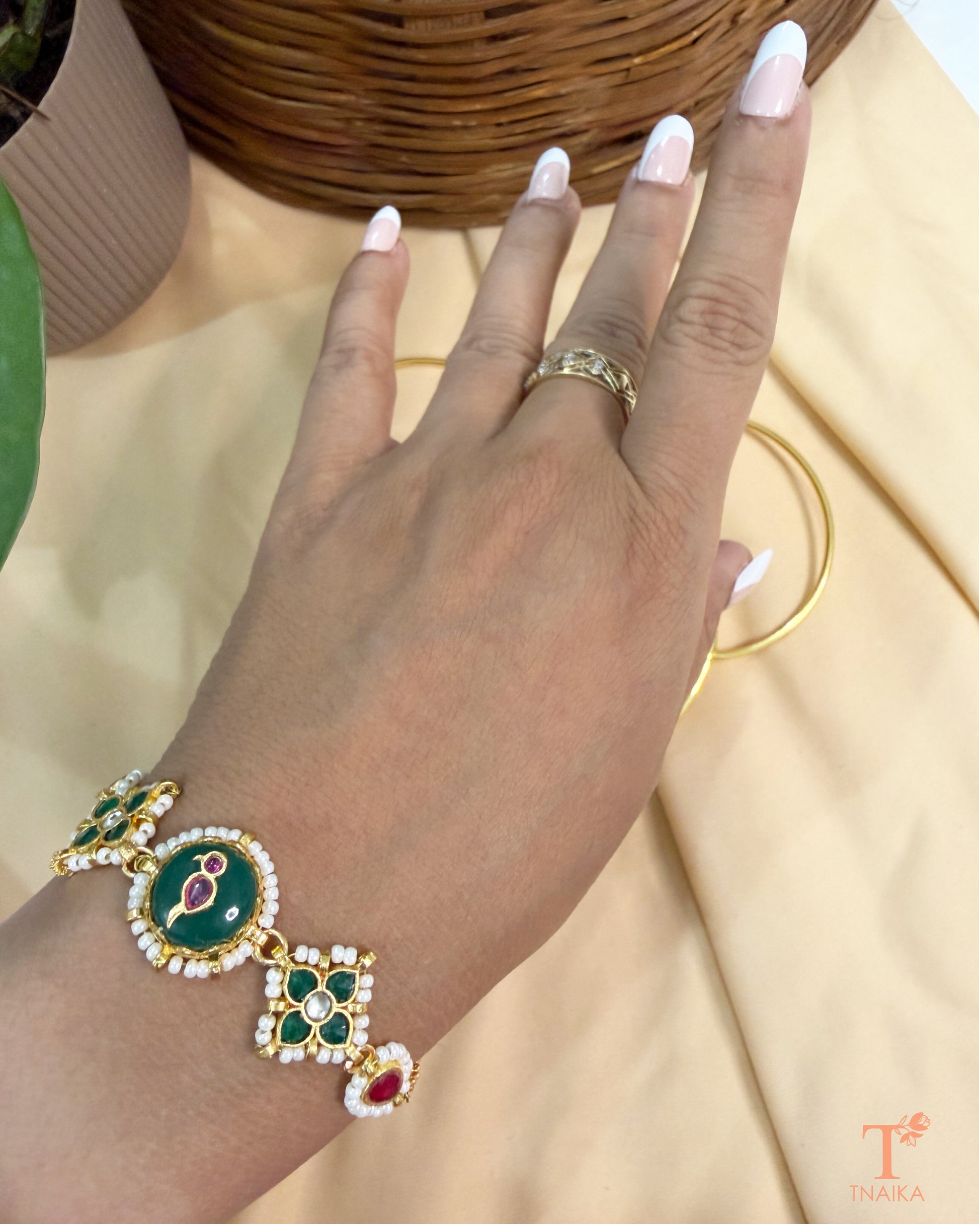 Adjustable gold finish brass bracelet featuring green enamel and handcrafted kundan detailing.