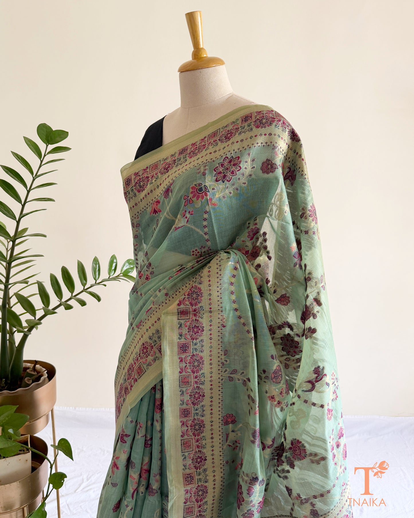 Mint green printed linen cotton saree with ornate border and graceful drape.