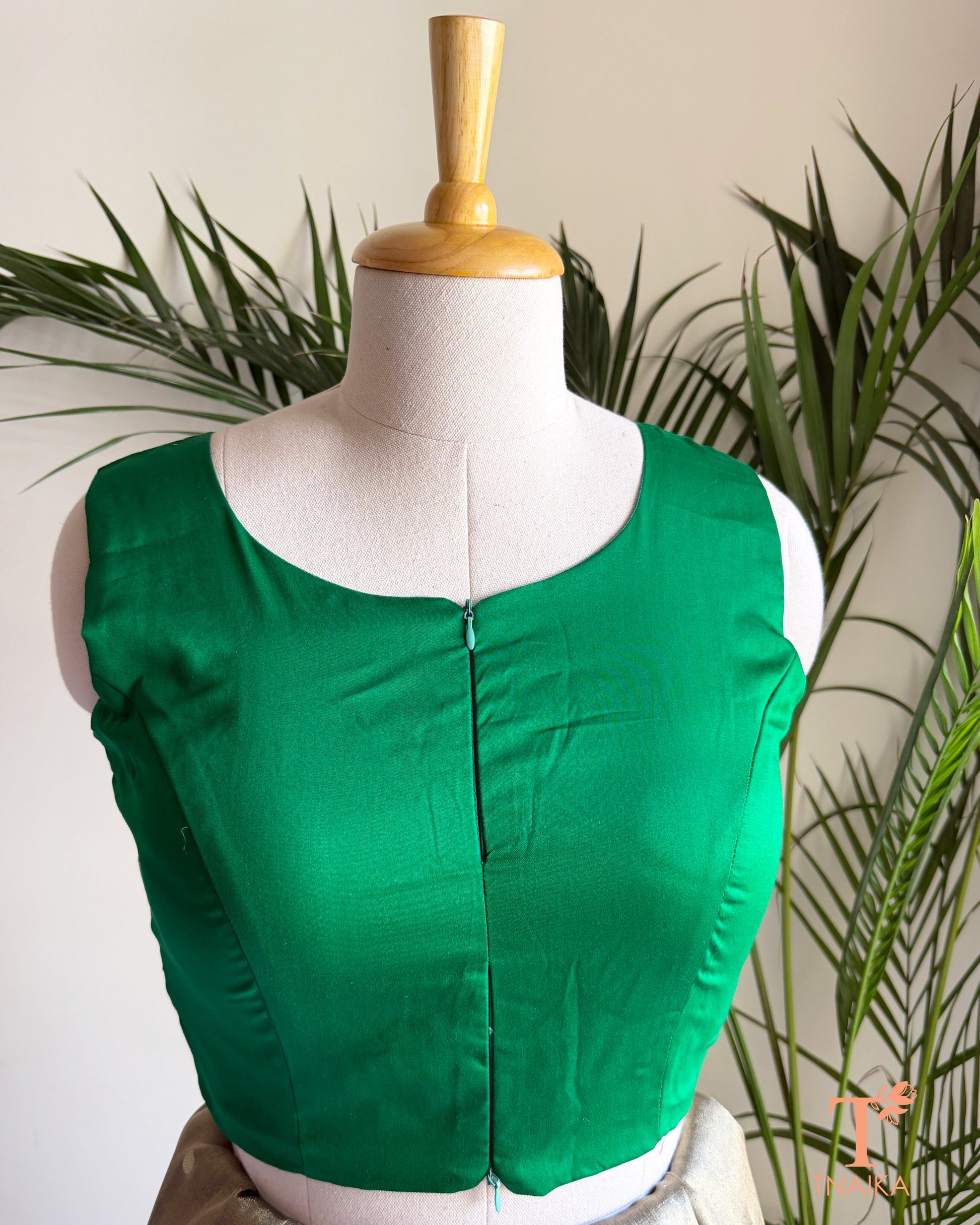 Close-up of the contemporary notched neckline and dual front zip detail on the premium emerald green blouse.