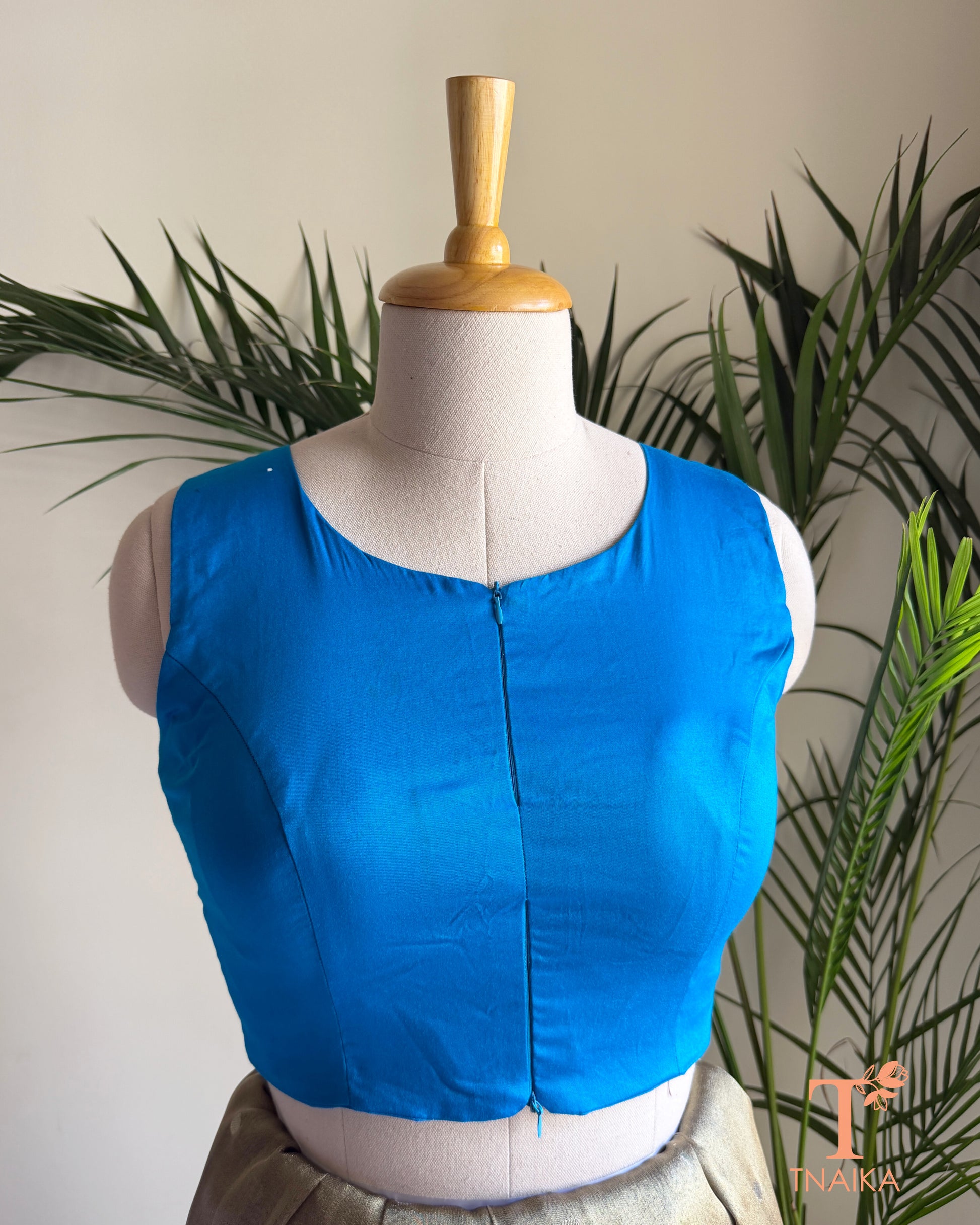 Close-up of the contemporary notched neckline and dual front zip detail on the premium emerald green blouse.
