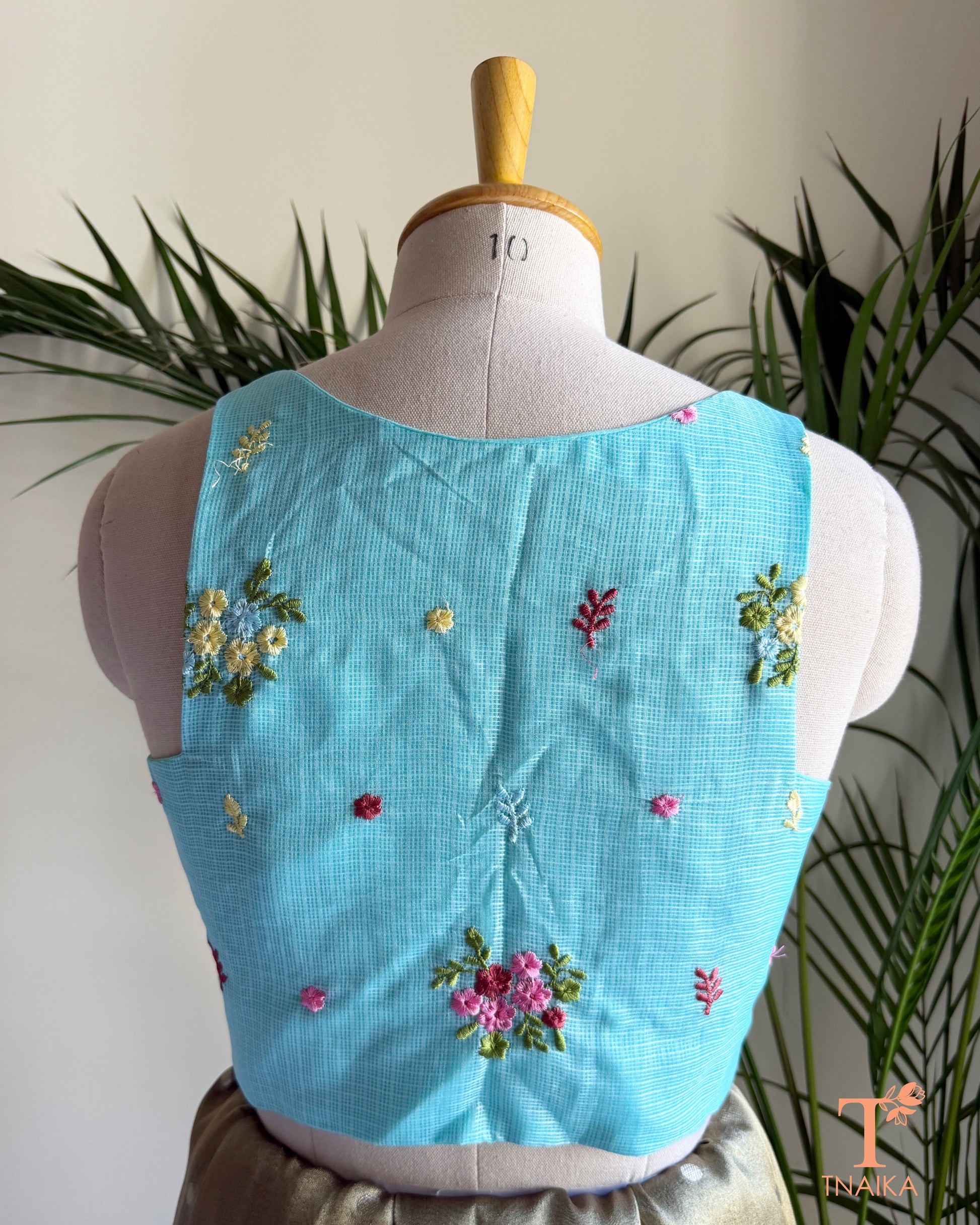 Back view of premium embroidered Kota silk blouse featuring delicate floral motifs, soft pastel embroidery, and a structured tailored finish.
