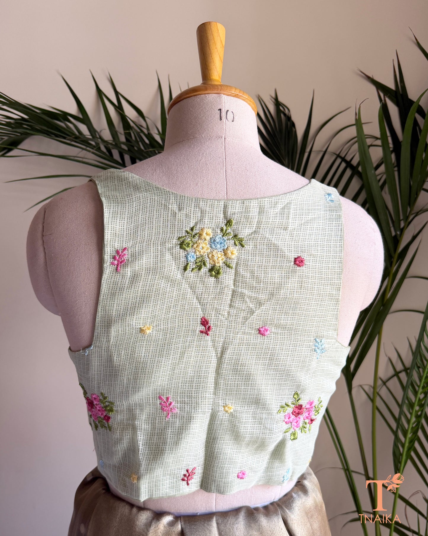 Back view of premium embroidered Kota silk blouse featuring delicate floral motifs, soft pastel embroidery, and a structured tailored finish.