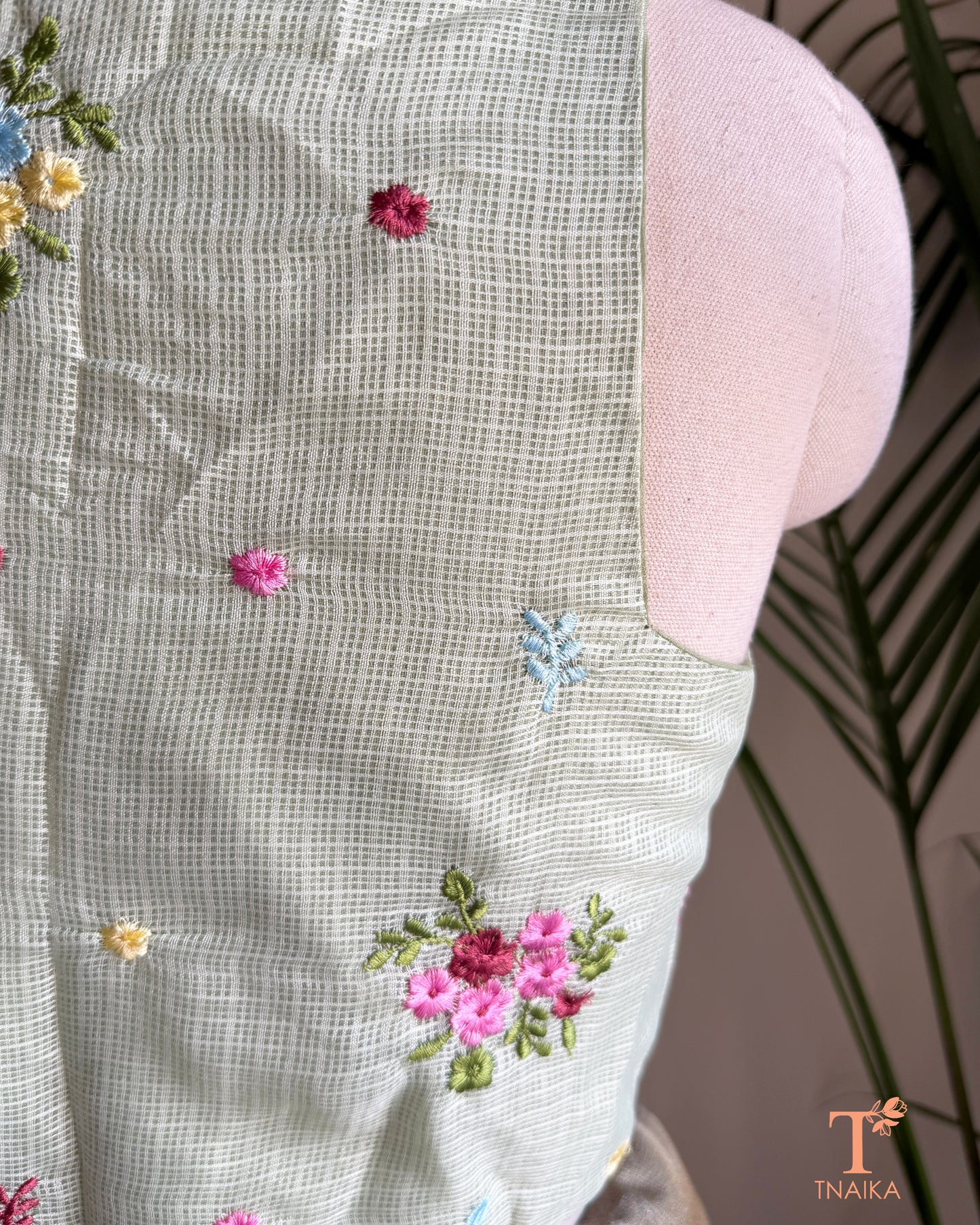 Close-up of premium Kota silk blouse showcasing handcrafted floral embroidery and fine textured fabric.