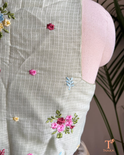 Close-up of premium Kota silk blouse showcasing handcrafted floral embroidery and fine textured fabric.