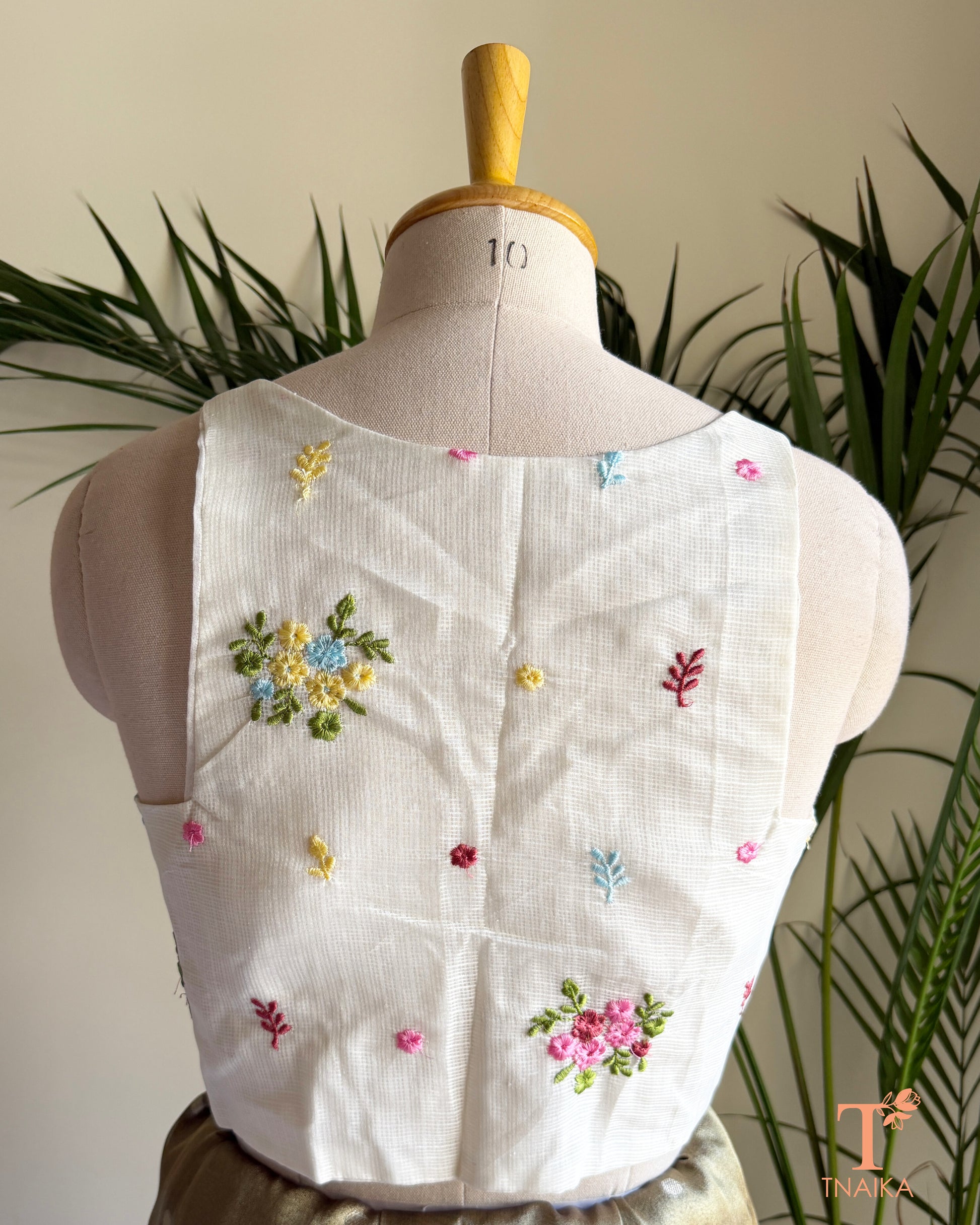 Back view of premium embroidered Kota silk blouse featuring delicate floral motifs, soft pastel embroidery, and a structured tailored finish.