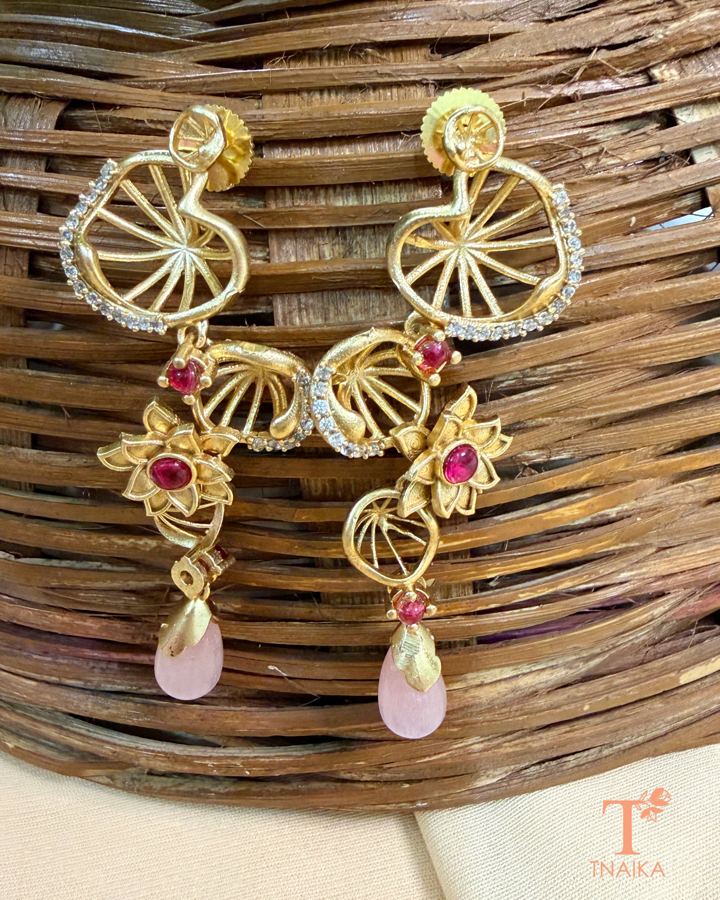 Statement brass dangler earrings featuring AD stones and decorative floral accents.