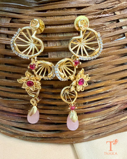 Statement brass dangler earrings featuring AD stones and decorative floral accents.