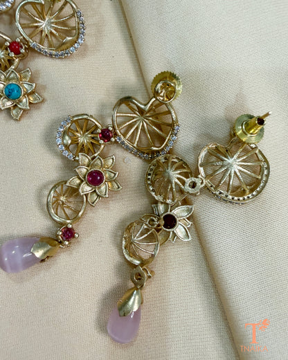 Elegant floral statement earrings with ruby-toned centre stones, gold finish and soft pink hanging drops for festive wear.