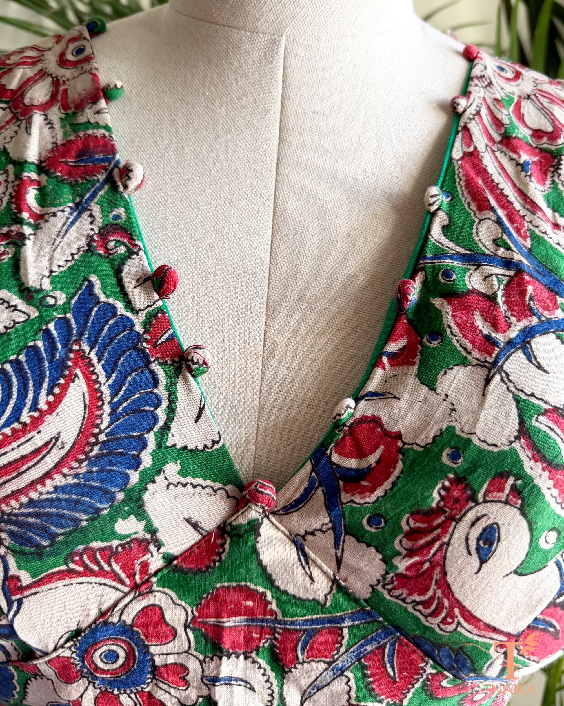 Detailed view of the V-neckline with handcrafted fabric potli embellishments on a multicolor Kalamkari cotton blouse by Tnaika™.