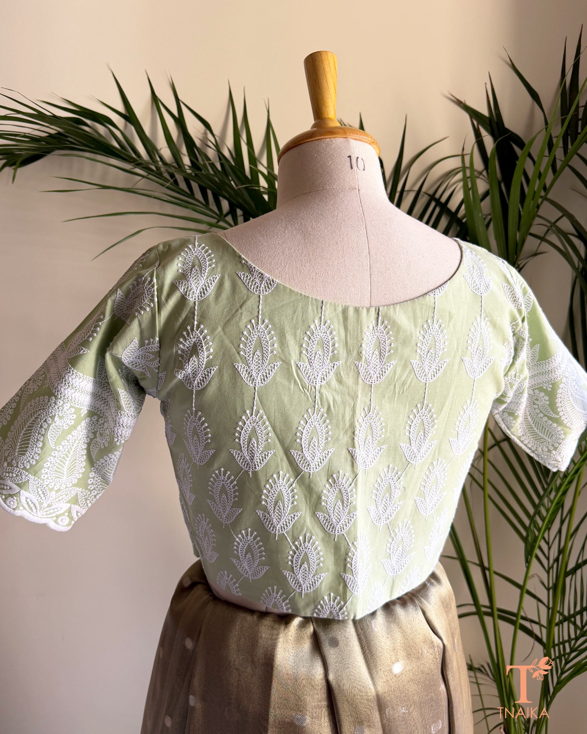 Detailed view of Chikankari-inspired white machine embroidery on premium pistachio green cotton fabric with elegant floral motifs.