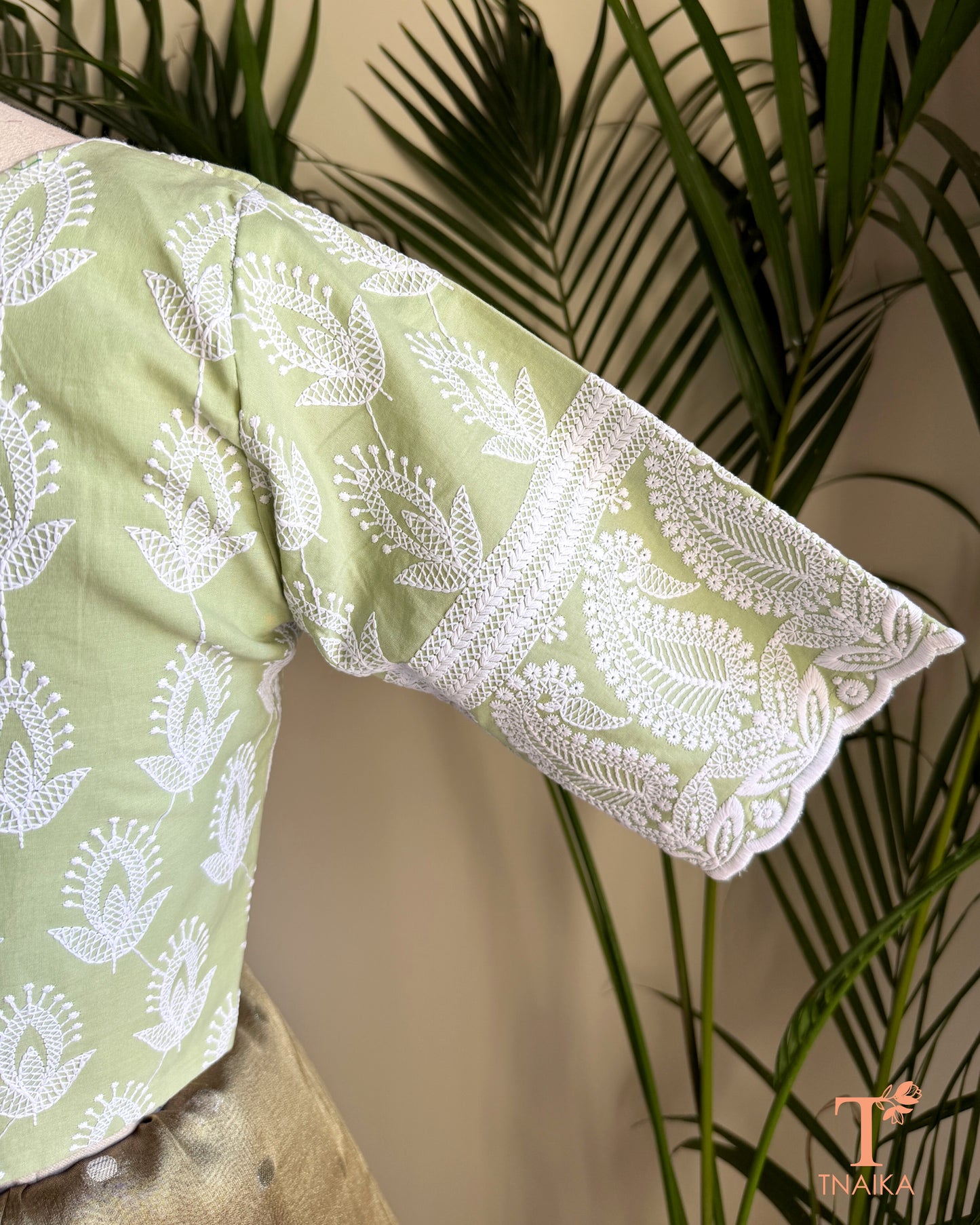 Close-up of the embroidered elbow-length sleeve with intricate Chikankari-inspired white embroidery on a pistachio green cotton blouse.