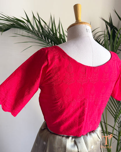 Back view of red embroidered cotton blouse featuring cutwork sleeves.
