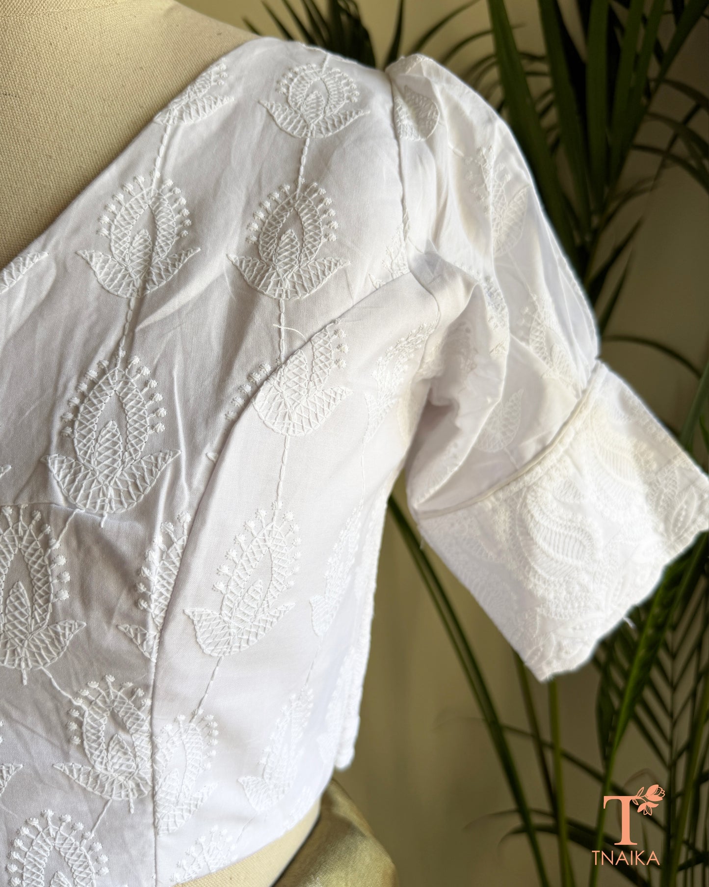 Side profile of white cotton blouse showcasing embroidered puff sleeve detailing.