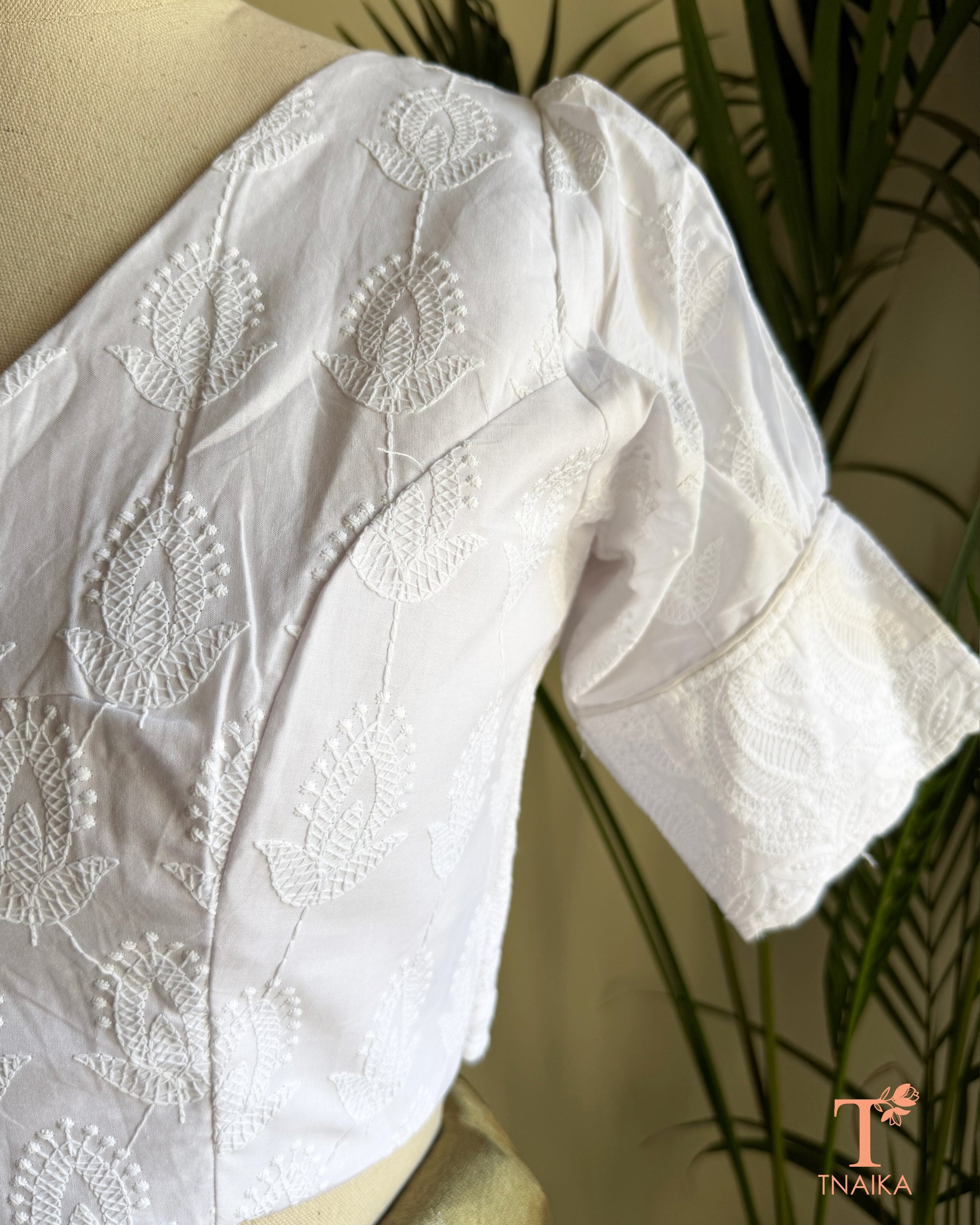 Side profile of white cotton blouse showcasing embroidered puff sleeve detailing.