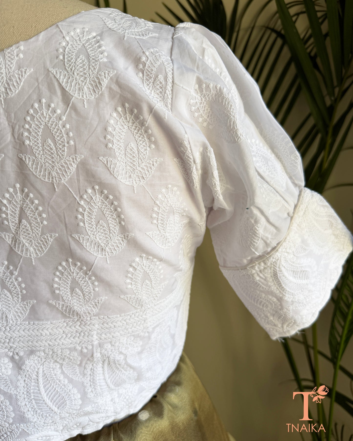 Close-up of Chikankari inspired machine embroidery on white cotton puff sleeve blouse.