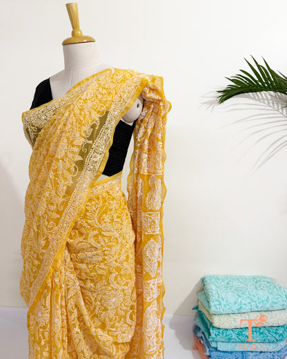 Yellow georgette saree with handcrafted paisley and floral embroidery.