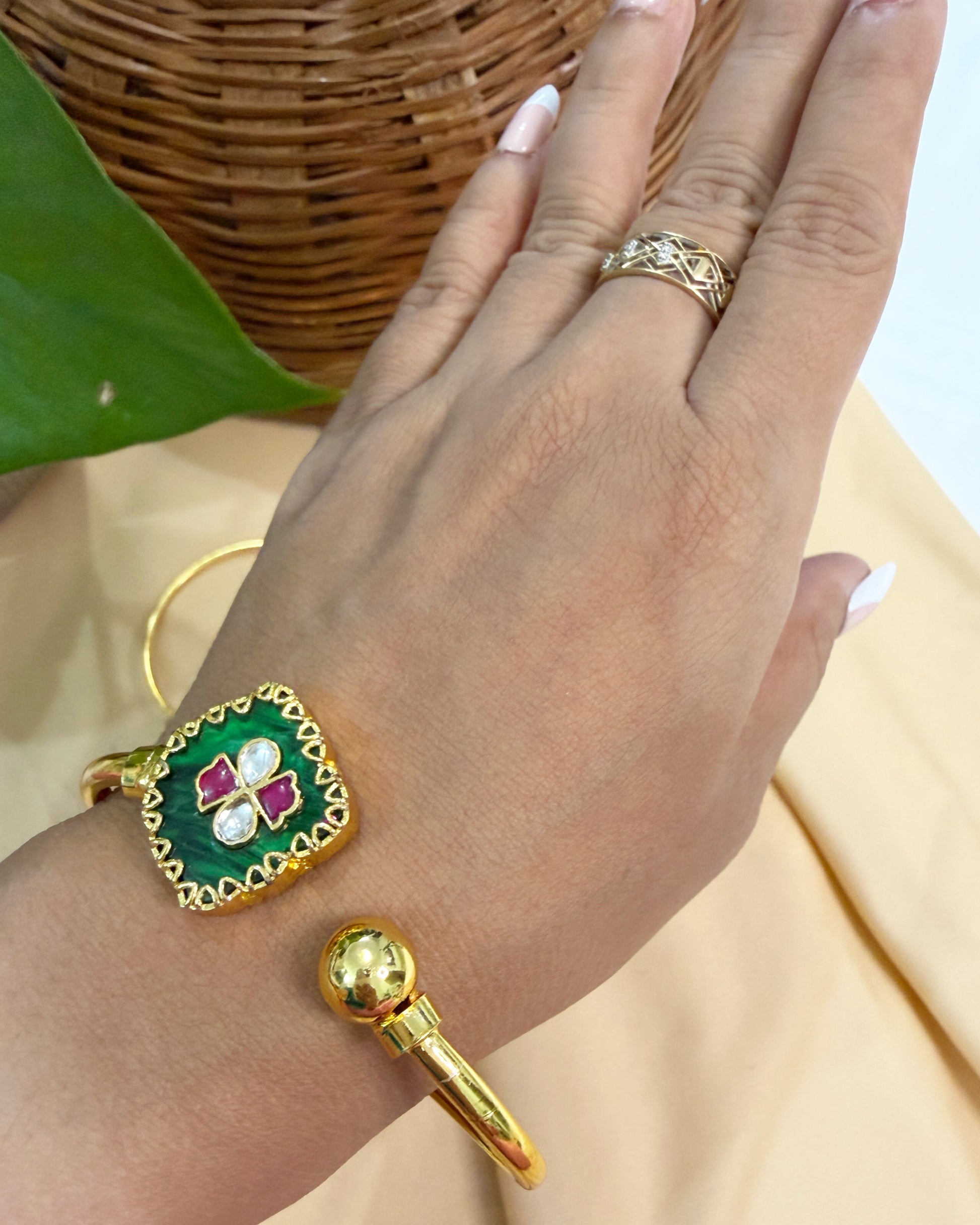 Adjustable gold finish brass bracelet featuring green enamel and handcrafted kundan detailing.