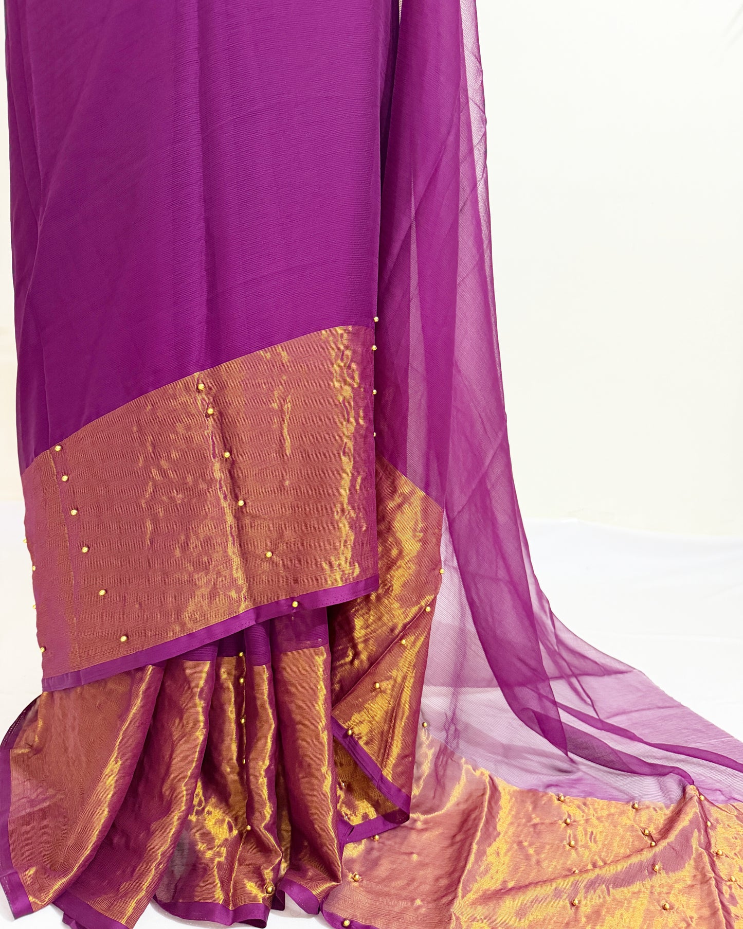 Elegant pearl pinned chiffon saree featuring a metallic gold border.