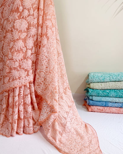 Premium blush peach Chikankari saree with all-over floral embroidery and artisan craftsmanship.