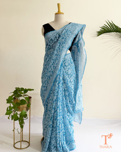 Handcrafted powder blue Chikankari saree with delicate white embroidery and floral patterns.